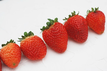 Raw of Fresh Strawberry Fruits with Green Leaves isolated on white background