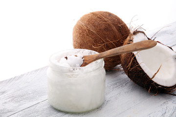 coconut and opened glass jar with fresh coconut oil on wooden background.