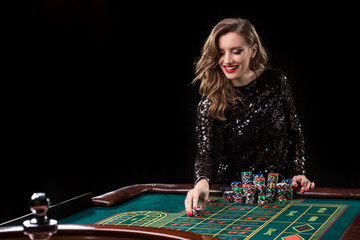 Woman playing in casino. Woman stakes piles of chips playing rou