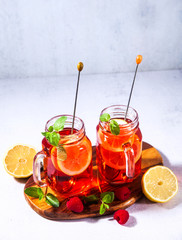 Iced tea with orange and raspberry in two glasses and mint