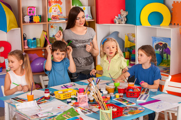 Kids playroom organization of children painting and drawing in kid's club. Craft lesson in primary...
