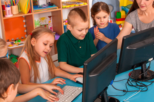 Children computer class us for education and video game. Boys and girls in children's club developing computer games nearby screen. New technologies alternative to classical training.
