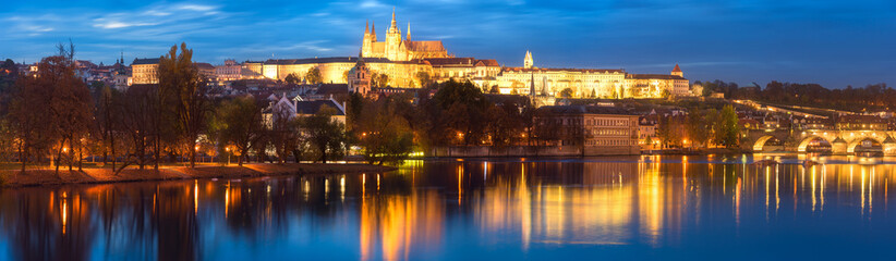 Fototapeta na wymiar Large panorama of Prague, view of illuminated Prague castle (Prazsky Hrad) with reflection in the water, night scenic cityscape, world famous historical heritage of Czech Republic