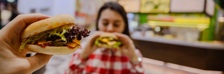 couple eat cheeseburgers in cafe