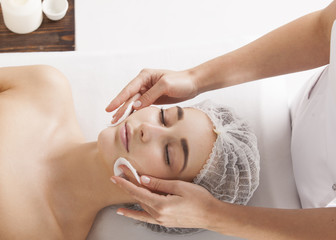 The beautician removes the face pack from the client's face.