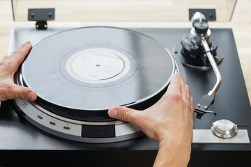 Hands placing record on turntable close-up