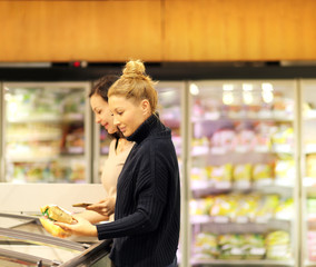 Woman choosing frozen food from a supermarket freezer