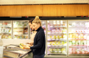 Woman choosing frozen food from a supermarket freezer