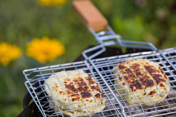 Top view on two grilled slices of homemade halloumi cheese on grill. Outdoors..Grilling season.