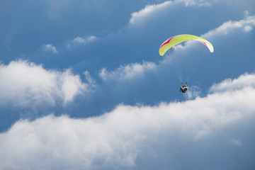 Paragliding above mountain peaks and clouds during winter sunny snowy day