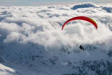 Paragliding above mountain peaks and clouds during winter sunny snowy day © sefoma