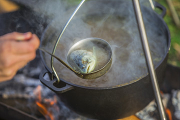 Fish soup boils in cauldron at the stake. Soup in a pot in the fire