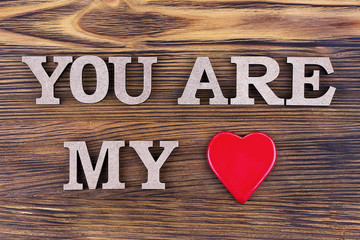 Valentines day background lettering I Love on brown wooden background.