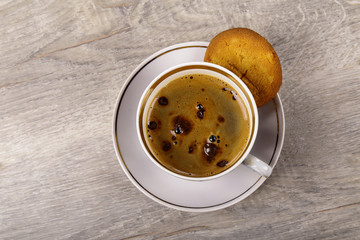 A cup of coffee and a cookie on a wooden background