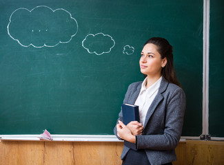 dreamy teacher standing at the blackboard