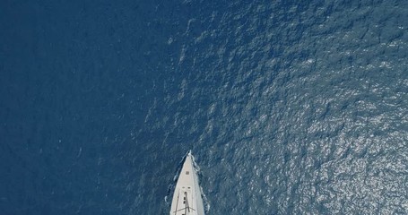 Perpendicular aerial view of a sailing boat navigating slowly. - Powered by Adobe