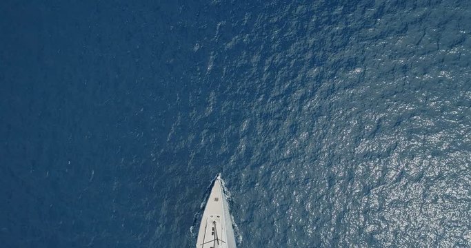 Perpendicular aerial view of a sailing boat navigating slowly.
