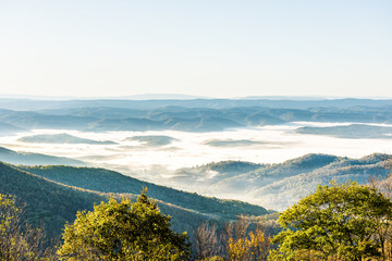 Overlook of West Virginia mountains in autumn fall with foliage and mist fog clouds covering valley...