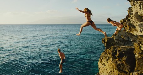 Friends cliff jumping into the ocean at sunset - Powered by Adobe