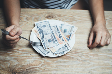 The girl with the fork next to the plate with money on black background