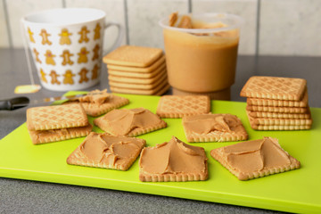 Peanut butter on cookies. Cookies with peanut butter on bright green board.