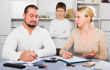 Parents calculating family budget while son standing behind