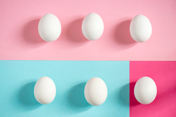 Fresh white eggs over blue and pink background