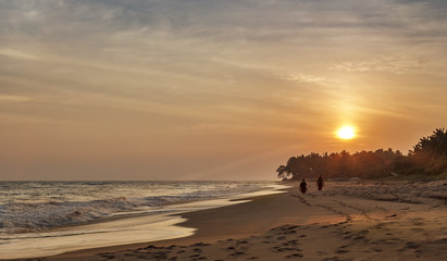 Golden sunset on Sri Lanka with two people on the beach