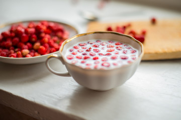 Wild strawberry with milk on a wooden background