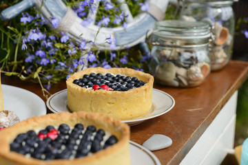 Two cheesecake with fresh blueberries and raspberries on a wooden background