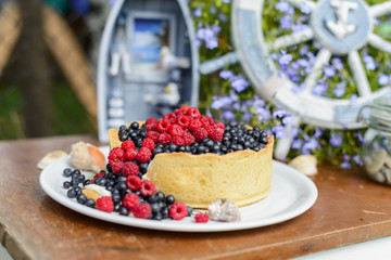 Tasty cheesecake with fresh blueberries and raspberries on a wooden background