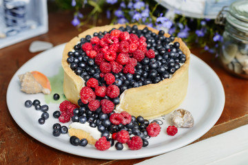 Tasty cheesecake with fresh blueberries and raspberries on a wooden background
