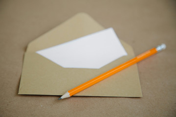 A vintage brown table and an envelope with a yellow pencil.