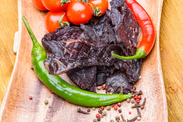 Beef jerky with vegetables and spices on a wooden tray