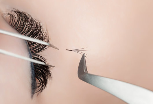 Fototapeta Eyelash extension procedure close up. Beautiful Woman with long lashes in a beauty salon.