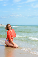A beautiful woman in a red sweater sitting on the beach of Odessa in Ukraine