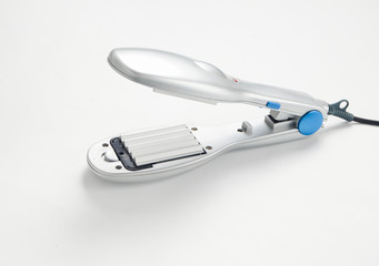A hair iron for silver color on a white background. Hair care.