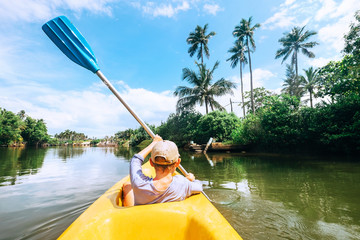 Boy sailing in canoe boat on tropical lagoon