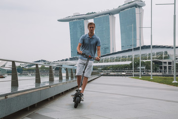 Young man riding an electric scooter in Singapore with an amazing view on the city.  © Aerial Film Studio