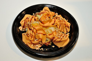 Detail of a salmon cooked plate decorated by a chef with pineapple, cheese shavings and balsamic glaze.