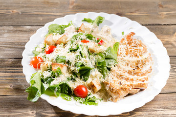 Caesar Salad with parmesan cheese and croutons. Grilled chicken breasts and fresh romaine lettuce in plate