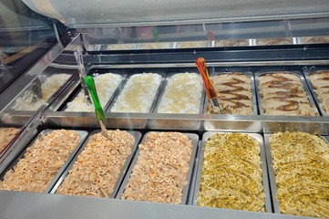 Detail of the inside window of an ice-cream maker showing the trays with various flavors. Among the varieties of ice cream present there are chocolate, pistachio, cream and hazelnut.