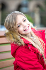 Obraz premium Girl in red coat sit on bench in park