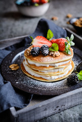 American pancakes with whipped cream, strawberries, blackberries, walnuts and powdered sugar