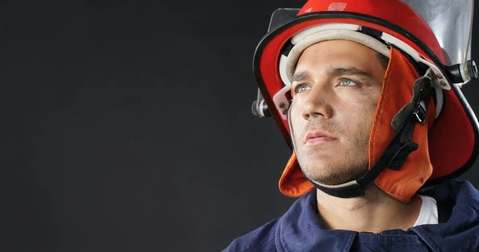 Thoughtful fireman standing against black background  