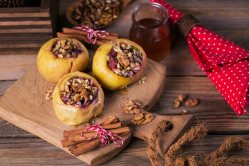 Baked apples stuffed with berries, walnuts and honey on a wooden cutting board.