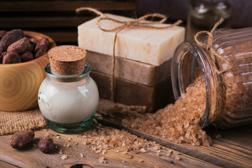 Natural cosmetic oil, sea salt and natural handmade soap with cocoa beans on rustic wooden background