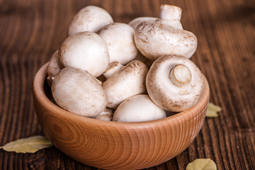 champignons white mushrooms in wooden bowl on wood table background