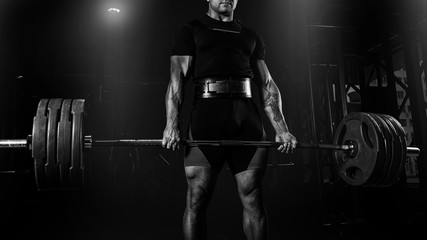 Professional athlete is standing and is holding a very heavy barbell.