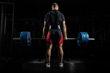 Professional athlete is standing and is holding a very heavy barbell.